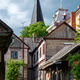 Old wooden buildings stand in a quiet street with a tall church tower nearby Old wooden buildings stand in a quiet street with a tall church tower nearby - PhotoDune Item for Sale