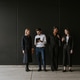 Group of four professionals standing against a black wall, engaged in conversation. Diverse team wit Group of four professionals standing against a black wall, engaged in conversation. Diverse team wit - PhotoDune Item for Sale
