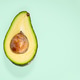 Half avocado with seed on mint green background Half avocado with seed on mint green background - PhotoDune Item for Sale