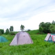 Three tents on grassy field, natural open air campsite, surrounding landscape for tourism, adventure Three tents on grassy field, natural open air campsite, surrounding landscape for tourism, adventure - PhotoDune Item for Sale
