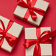 Gift boxes in beige packaging with red satin bows on a bright red background Gift boxes in beige packaging with red satin bows on a bright red background - PhotoDune Item for Sale