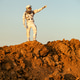 Astronaut stands on Martian surface pointing towards horizon during exploration in daylight Astronaut stands on Martian surface pointing towards horizon during exploration in daylight - PhotoDune Item for Sale