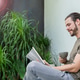 Young bearded man sitting on a couch at home reading a book Young bearded man sitting on a couch at home reading a book - PhotoDune Item for Sale