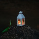 A decorative white lantern with a glowing candle placed on a dark rock by a pond at dusk. Romantic a A decorative white lantern with a glowing candle placed on a dark rock by a pond at dusk. Romantic a - PhotoDune Item for Sale