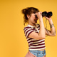 Young woman joyfully exploring her surroundings with binoculars against a lively backdrop Young woman joyfully exploring her surroundings with binoculars against a lively backdrop - PhotoDune Item for Sale