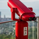 Bright red observation binoculars on rooftop deck overlooking city skyline. Bright red observation binoculars on rooftop deck overlooking city skyline. - PhotoDune Item for Sale