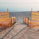 Temporary fencing marks access to a quiet sandy beach with a wooden walkway and calm sea in the dist Temporary fencing marks access to a quiet sandy beach with a wooden walkway and calm sea in the dist - PhotoDune Item for Sale
