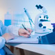 Laboratory Scientist Writing Notes on Clipboard with Microscope and Blood Test Tubes in Background Laboratory Scientist Writing Notes on Clipboard with Microscope and Blood Test Tubes in Background - PhotoDune Item for Sale