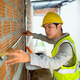 Young Asian Engineer Measuring Brick Wall at Construction Site with Tape Measure and Safety Vest Young Asian Engineer Measuring Brick Wall at Construction Site with Tape Measure and Safety Vest - PhotoDune Item for Sale