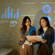 Two Businesswomen Reviewing Data During Office Presentation with Projected Charts and Analytics Dash Two Businesswomen Reviewing Data During Office Presentation with Projected Charts and Analytics Dash - PhotoDune Item for Sale