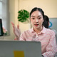 Asian Businesswoman Talking and Gesturing During Video Call at Office Desk with Data Dashboard on Mo Asian Businesswoman Talking and Gesturing During Video Call at Office Desk with Data Dashboard on Mo - PhotoDune Item for Sale