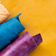 Colorful Rolled Leather Hides in Orange Blue and Purple Tones on Yellow Background Colorful Rolled Leather Hides in Orange Blue and Purple Tones on Yellow Background - PhotoDune Item for Sale
