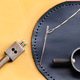 Leather Stitching Needle and Thread on Navy Blue Round Leather Piece with Hole Punch Tool on Yellow Leather Stitching Needle and Thread on Navy Blue Round Leather Piece with Hole Punch Tool on Yellow - PhotoDune Item for Sale