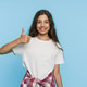 Mixed race schoolgirl in white t-shirt showing thumbs up on blue studio background Mixed race schoolgirl in white t-shirt showing thumbs up on blue studio background - PhotoDune Item for Sale
