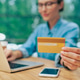 Close up of credit card in female hand while young woman using laptop in coworking space Close up of credit card in female hand while young woman using laptop in coworking space - PhotoDune Item for Sale