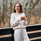 Relaxed woman enjoying morning drink on wooden deck surrounded by trees Relaxed woman enjoying morning drink on wooden deck surrounded by trees - PhotoDune Item for Sale