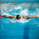 Tattooed male swimmer performing butterfly stroke in indoor pool Tattooed male swimmer performing butterfly stroke in indoor pool - PhotoDune Item for Sale
