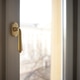 Close-up view of a golden window handle on a white window frame with blurred background of a buildin Close-up view of a golden window handle on a white window frame with blurred background of a buildin - PhotoDune Item for Sale