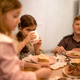Three children enjoying a meal at a table with plates of food, one child drinking from a cup, soft l Three children enjoying a meal at a table with plates of food, one child drinking from a cup, soft l - PhotoDune Item for Sale