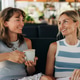 Two young women are sitting in an outdoor café, drinking coffee and chatting. Friends enjoying happy Two young women are sitting in an outdoor café, drinking coffee and chatting. Friends enjoying happy - PhotoDune Item for Sale