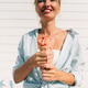 Woman holds a melting strawberry ice cream cone toward the camera. Woman holds a melting strawberry ice cream cone toward the camera. - PhotoDune Item for Sale