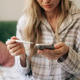 A woman measures her temperature with a digital thermometer and uses online chat to consult with a h A woman measures her temperature with a digital thermometer and uses online chat to consult with a h - PhotoDune Item for Sale