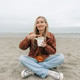 Full-length portrait of a woman sitting on pebbles on the beach and eating Asian noodles from a box. Full-length portrait of a woman sitting on pebbles on the beach and eating Asian noodles from a box. - PhotoDune Item for Sale