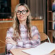 An attractive business woman wearing glasses sits in a cafe and smiles at the camera. An attractive business woman wearing glasses sits in a cafe and smiles at the camera. - PhotoDune Item for Sale