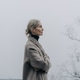 Woman in a coat on a rural road in foggy weather. Psychological relaxation in the surrounding area. Woman in a coat on a rural road in foggy weather. Psychological relaxation in the surrounding area. - PhotoDune Item for Sale