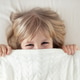 Portrait little girl peeking out blanket on bed. Cute kid smiling hiding under knitted cover. Playfu Portrait little girl peeking out blanket on bed. Cute kid smiling hiding under knitted cover. Playfu - PhotoDune Item for Sale