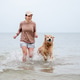 Woman running with Golden Retriever dog in the shallow sea Woman running with Golden Retriever dog in the shallow sea - PhotoDune Item for Sale