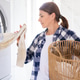 Woman loads laundry into washing machine in bright home Woman loads laundry into washing machine in bright home - PhotoDune Item for Sale