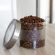 Glass jar filled with aromatic coffee beans rests on wooden surface. Glass jar filled with aromatic coffee beans rests on wooden surface. - PhotoDune Item for Sale