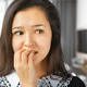 Young woman biting her nails while sitting in a modern indoor setting during the daytime Young woman biting her nails while sitting in a modern indoor setting during the daytime - PhotoDune Item for Sale