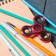 Fidget spinner sits among pens and pencils on a desk with a notebook nearby Fidget spinner sits among pens and pencils on a desk with a notebook nearby - PhotoDune Item for Sale