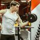 Workout session at the gym with a young man lifting a dumbbell in front of a weight rack Workout session at the gym with a young man lifting a dumbbell in front of a weight rack - PhotoDune Item for Sale