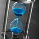 Hourglass with blue sand on a dark surface showing the passage of time in a simple design and modern Hourglass with blue sand on a dark surface showing the passage of time in a simple design and modern - PhotoDune Item for Sale