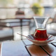 Turkish teacup Armudu with fresh tea at bottom stands in saucer on wooden table in cafe against boke Turkish teacup Armudu with fresh tea at bottom stands in saucer on wooden table in cafe against boke - PhotoDune Item for Sale