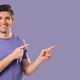 Young Smiling Man Presenting Something Isolated On Violet Background. Portrait Young Smiling Man Presenting Something Isolated On Violet Background. Portrait - PhotoDune Item for Sale