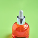Glass Dropper Bottle With Orange Liquid And Chrome Cap Standing On Green Background, Studio Product Glass Dropper Bottle With Orange Liquid And Chrome Cap Standing On Green Background, Studio Product - PhotoDune Item for Sale