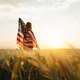Young Woman with the American flag running in a wheat field at sunset. 4th of July. Young Woman with the American flag running in a wheat field at sunset. 4th of July. - PhotoDune Item for Sale
