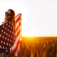 Young woman with American flag in a wheat field at sunset. 4th of July. Patriotic holiday. Young woman with American flag in a wheat field at sunset. 4th of July. Patriotic holiday. - PhotoDune Item for Sale