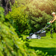 Man mows grass in a garden during a sunny day in the afternoon Man mows grass in a garden during a sunny day in the afternoon - PhotoDune Item for Sale