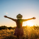 Woman raising arms in field during golden hour sunset Woman raising arms in field during golden hour sunset - PhotoDune Item for Sale