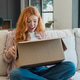 Excited woman unboxing package on couch at home Excited woman unboxing package on couch at home - PhotoDune Item for Sale