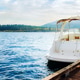 White motorboat moored at wooden pier on a beautiful lake with mountain background on a sunny day White motorboat moored at wooden pier on a beautiful lake with mountain background on a sunny day - PhotoDune Item for Sale