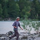 A man with a fishing rod runs along the shore against the backdrop of mountains A man with a fishing rod runs along the shore against the backdrop of mountains - PhotoDune Item for Sale