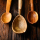Three handcrafted wooden spoons hanging on textured wooden surface Three handcrafted wooden spoons hanging on textured wooden surface - PhotoDune Item for Sale