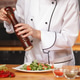 Chef adding pepper to fresh vegetable salad in kitchen. Chef adding pepper to fresh vegetable salad in kitchen. - PhotoDune Item for Sale