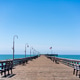 Wooden pier deck flanked by parallel rows of benches and streetlights facing the ocean horizon in Ca Wooden pier deck flanked by parallel rows of benches and streetlights facing the ocean horizon in Ca - PhotoDune Item for Sale